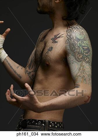 Picture - Bare chested young man with tattoos posing. Fotosearch