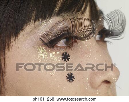 Close-up of woman's face with glitter, black snowflakes and false eyelashes View Large Photo Image Stock Photo - Close-up of woman's face with glitter, black snowflakes and false eyelashes. Fotosearch