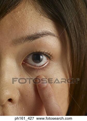 Close-up of woman's tugging at her lower eyelid View Large Photo Image Stock Photo - Close-up of woman's tugging at her lower eyelid. Fotosearch
