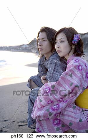 Stock Image - Couple at the beach during sunset. Fotosearch