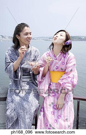 Stock Photograph - Couple enjoying a snack by the pier. Fotosearch