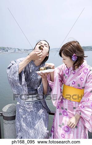 Stock Photography - Couple enjoying a snack by the pier. Fotosearch