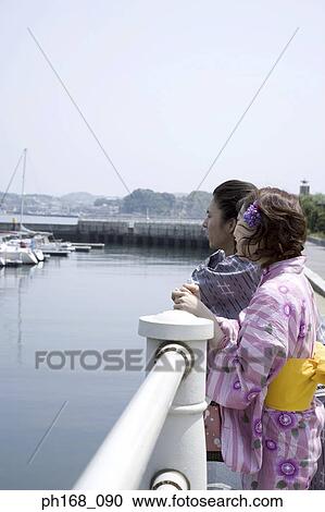 Stock Image - Couple enjoying the view at the pier. Fotosearch