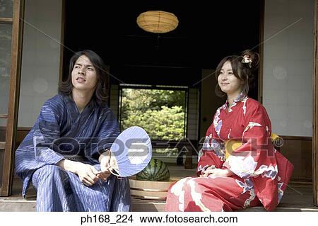 Picture - Couple in traditional Japanese clothing sitting by corridor with water melon. Fotosearch
