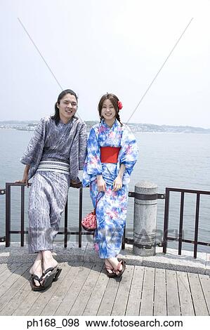 Stock Photo - Couple leaning against railing at the pier. Fotosearch