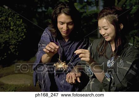 Stock Photo - Couple playing with sparklers at night. Fotosearch
