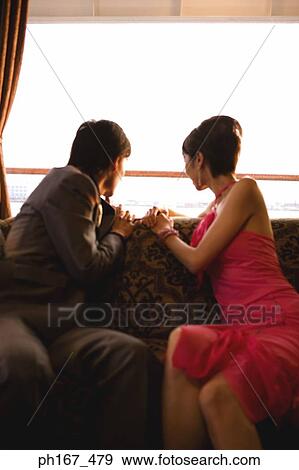Stock Photo - Couple sitting on couch, looking out of window. Fotosearch
