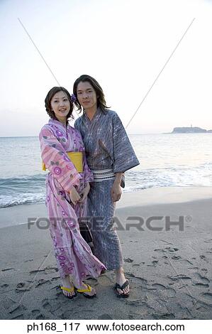 Couple standing by the beach during sunset View Large Photo Image Stock Photo - Couple standing by the beach during sunset. Fotosearch