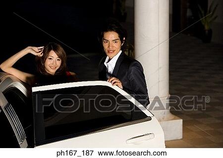 Couple standing next to limousine with door open View Large Photo Image Stock Photo - Couple standing next to limousine with door open. Fotosearch