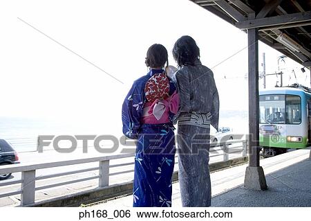 Stock Photograph - Couple waiting for train in traditional Japanese clothing, rear view. Fotosearch