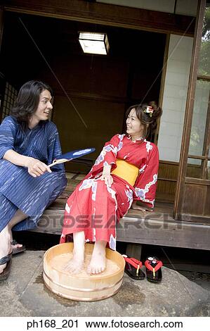 Stock Image - Man looking at woman soaking her feet in a tub. Fotosearch