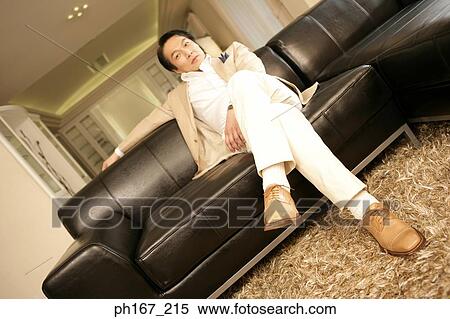 Man sitting at couch, low angle View Large Photo Image Stock Photography - Man sitting at couch, low angle. Fotosearch