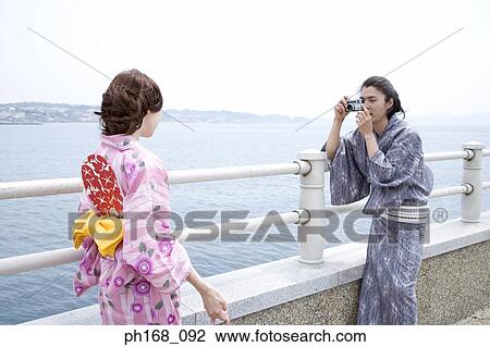 Stock Image - Man taking a picture of woman in kimono. Fotosearch