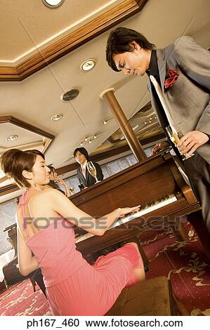 Man watching woman play the piano, with a couple standing by, low angle View Large Photo Image Stock Image - Man watching woman play the piano, with a couple standing by, low angle. Fotosearch