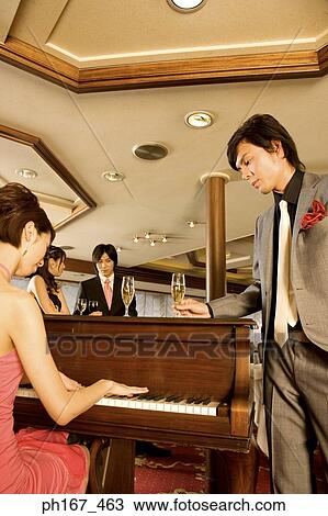 Man watching woman play the piano, with a couple standing by View Large Photo Image Stock Image - Man watching woman play the piano, with a couple standing by. Fotosearch