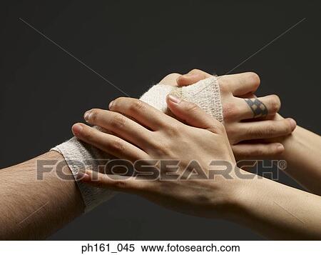 Stock Photography - Pair of hands holding another bandaged hand, close-up. Fotosearch