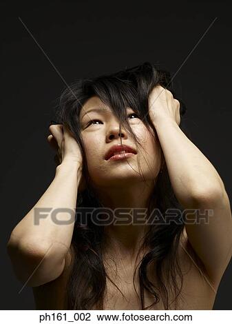 Stock Image - Portrait of a young woman pulling her long hair. Fotosearch