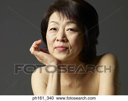 Stock Image - Portrait of mature woman with hand on chin. Close-up. Fotosearch