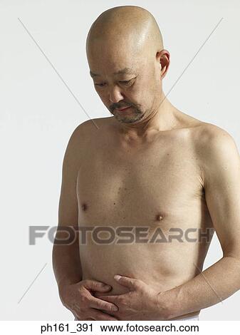 Stock Image - Shirtless bald man touching his stomach. Fotosearch