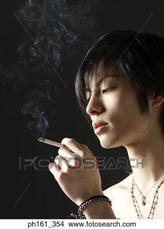 Picture - Shirtless young man holding a cigarette. Fotosearch