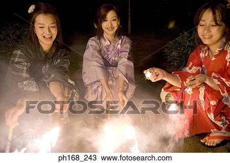 Three women playing with sparklers at night View Large Photo Image Stock Image - Three women playing with sparklers at night. Fotosearch