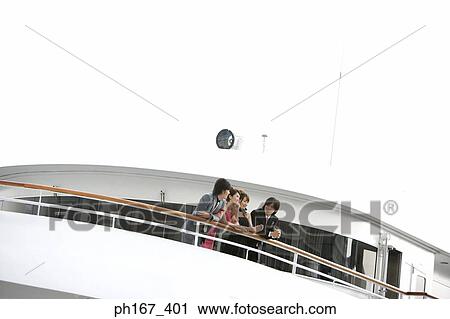 Stock Image - Two couple leaning on the railing onboard a cruise ship. Fotosearch