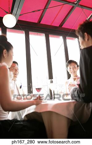 Stock Image - Two couples dining in a restaurant. Fotosearch