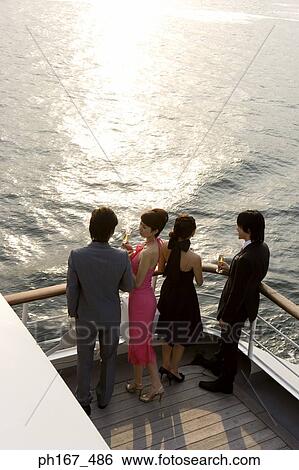 Stock Photograph - Two couples enjoying the sunset onboard a cruise ship, high angle view. Fotosearch