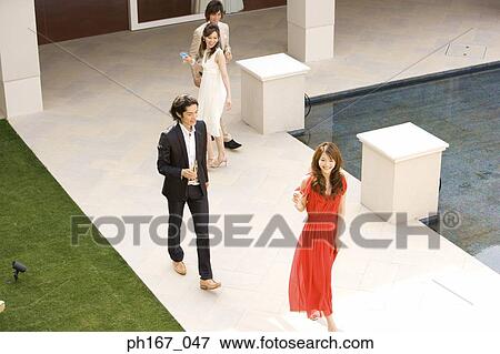 Two couples having cocktails and champagne in the courtyard, high angle View Large Photo Image Stock Photo - Two couples having cocktails and champagne in the courtyard, high angle. Fotosearch