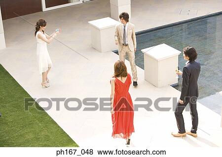 Two couples having cocktails and champagne in the courtyard, high angle View Large Photo Image Stock Photo - Two couples having cocktails and champagne in the courtyard, high angle. Fotosearch