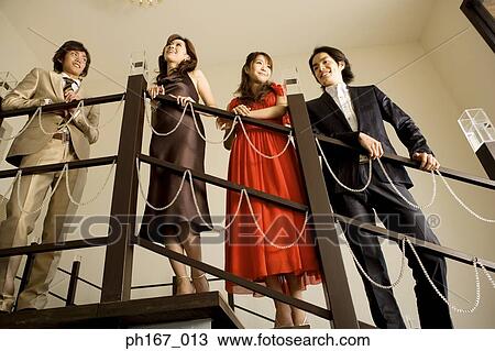 Stock Image - Two couples leaning against banister. Fotosearch