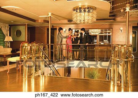 Stock Image - Two couples making a toast in the bar of cruise ship. Fotosearch
