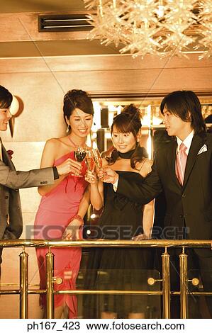 Stock Image - Two couples making a toast in the bar of cruise ship. Fotosearch