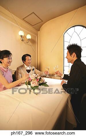 Two men and a woman having wine in a restaurant View Large Photo Image Stock Photograph - Two men and a woman having wine in a restaurant. Fotosearch