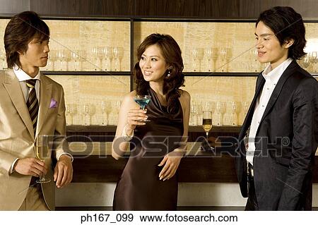 Two men and a woman relaxing by the bar View Large Photo Image Stock Photo - Two men and a woman relaxing by the bar. Fotosearch