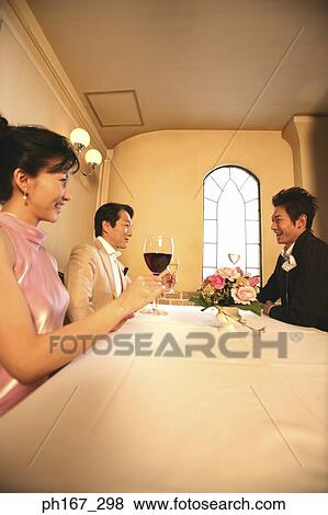 Two men and a woman toasting with wine, low angle view View Large Photo Image Stock Photo - Two men and a woman toasting with wine, low angle view. Fotosearch