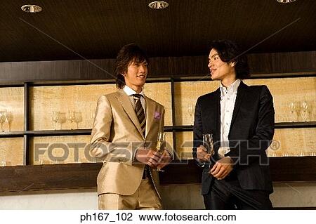 Stock Image - Two men relaxing by the bar, low angle. Fotosearch