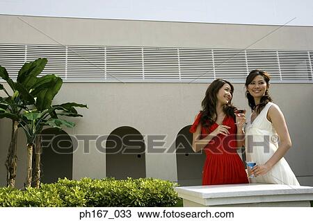 Stock Image - Two women having cocktails in the courtyard. Fotosearch
