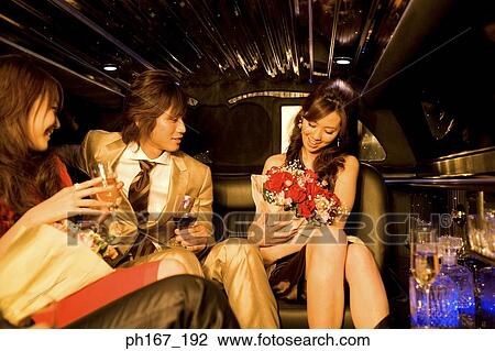 Two women, holding a bouquet of flowers each, and a man in a limousine View Large Photo Image Stock Image - Two women, holding a bouquet of flowers each, and a man in a limousine. Fotosearch