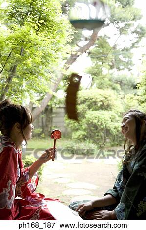 Stock Photo - Two women in kimono sitting by the corridor. Fotosearch