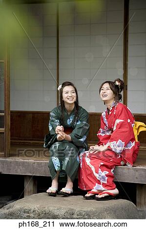 Stock Image - Two women sitting by the corridor, smiling. Fotosearch