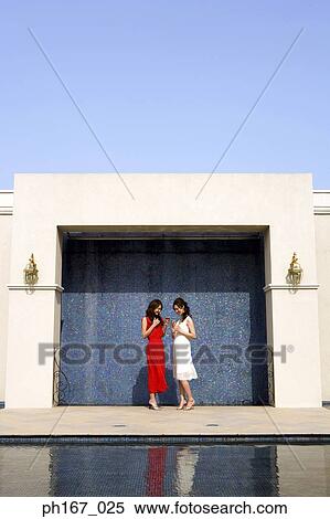 Two women standing against tiled wall View Large Photo Image Stock Photography - Two women standing against tiled wall. Fotosearch