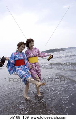 Stock Photo - Two women taking a walk by the beach. Fotosearch