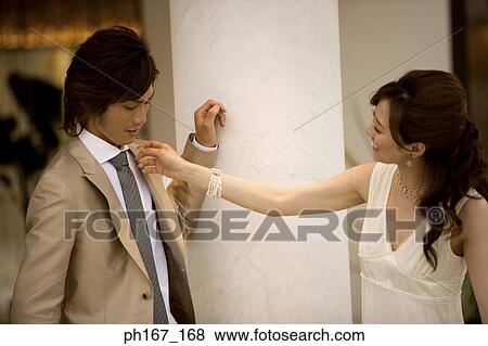 Stock Photo - Woman adjusting man's clothes. Fotosearch
