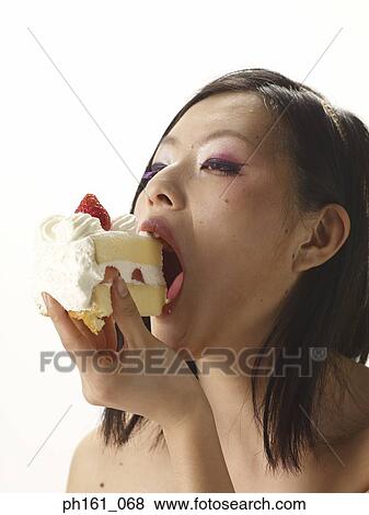 Stock Photo - Woman biting into a cake. Fotosearch