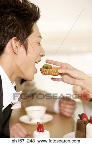 Woman feeding a young man pastry View Large Photo Image Stock Photo - Woman feeding a young man pastry. Fotosearch