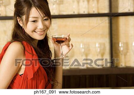 Woman holding a cocktail, relaxing by bar View Large Photo Image Stock Image - Woman holding a cocktail, relaxing by bar. Fotosearch