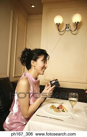 Woman holding a gift by the dining table View Large Photo Image Stock Photograph - Woman holding a gift by the dining table. Fotosearch