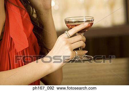 Woman holding a glass of cocktail, close-up View Large Photo Image Stock Image - Woman holding a glass of cocktail, close-up. Fotosearch