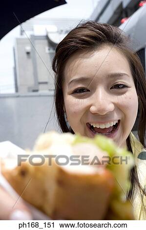 Stock Image - Woman holding a sandwich, smiling. Fotosearch